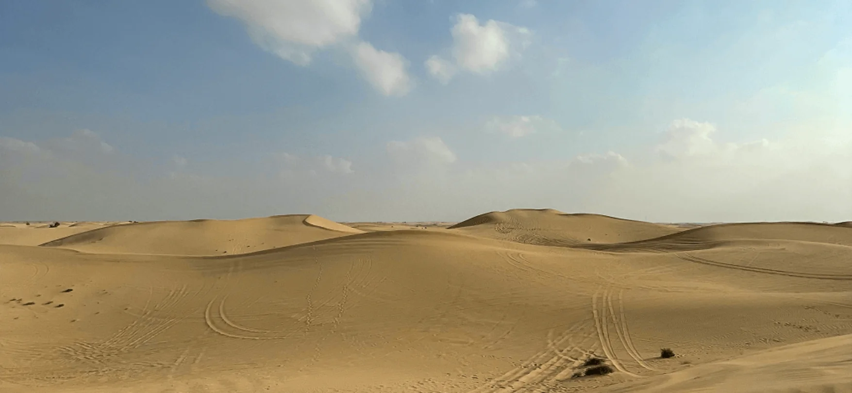 Goldene Sanddünen in der Wüste zwischen Abu Dhabi und Dubai unter blauem Himmel