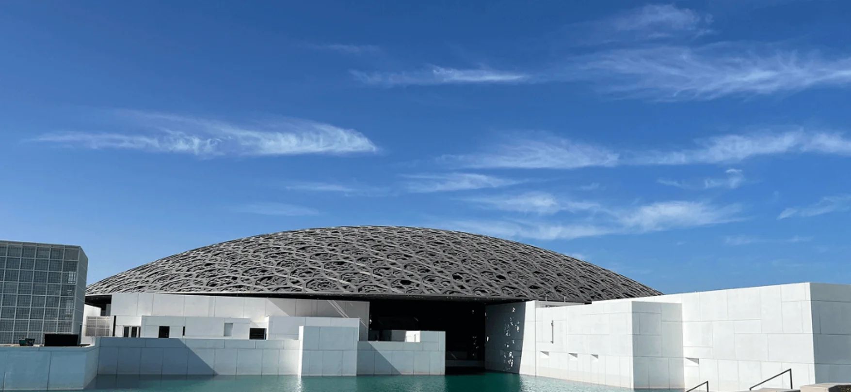 Moderne Architektur des Louvre Abu Dhabi mit Kuppeldach und Wasserreflexion