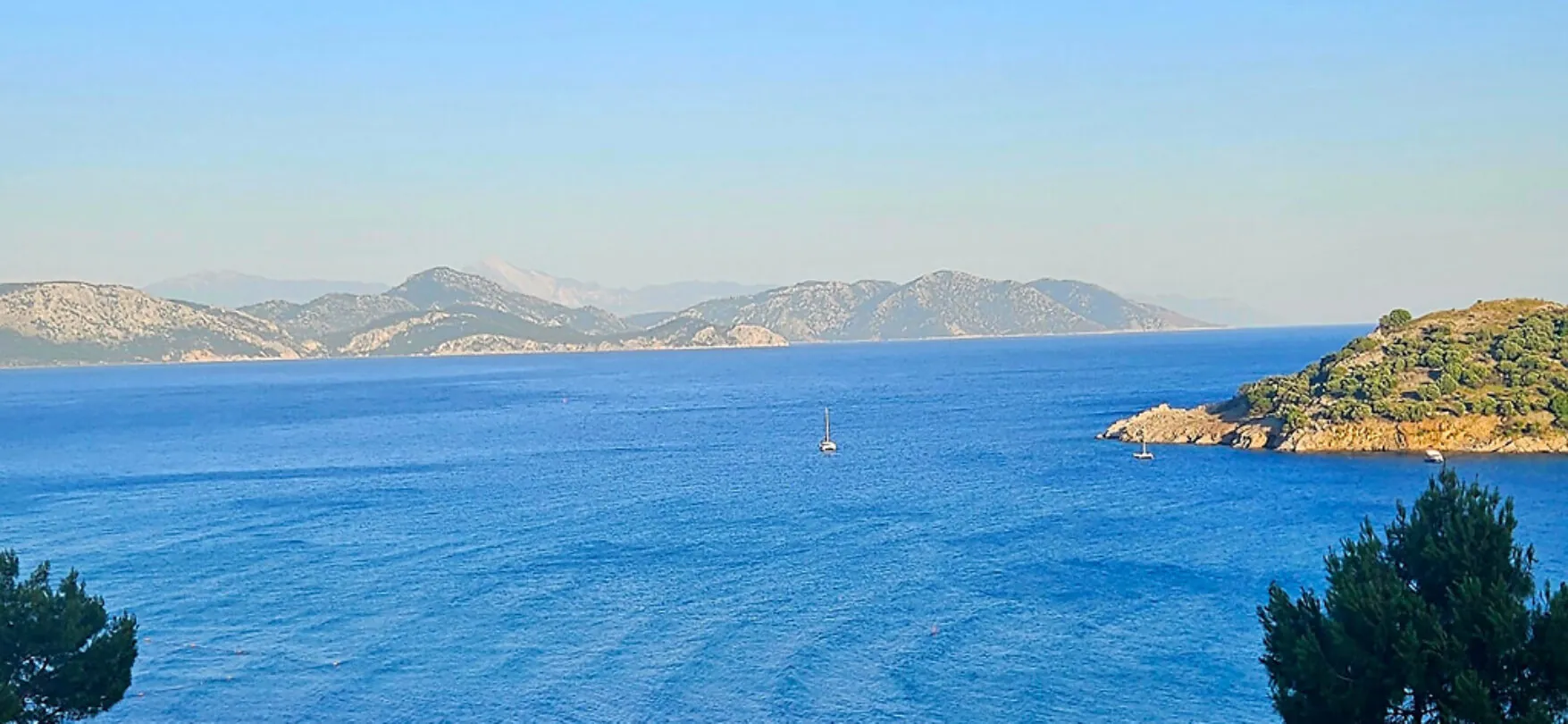 Bucht von Sarigerme mit tiefblauem Meer und grünen Hügeln im Hintergrund