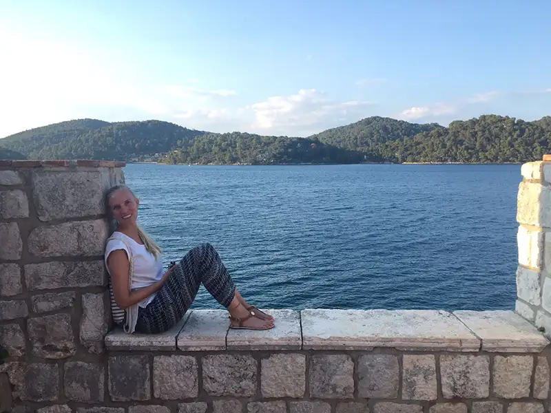 Reiseberaterin Julia Huber sitzt entspannt am Meer während der Blauen Reise