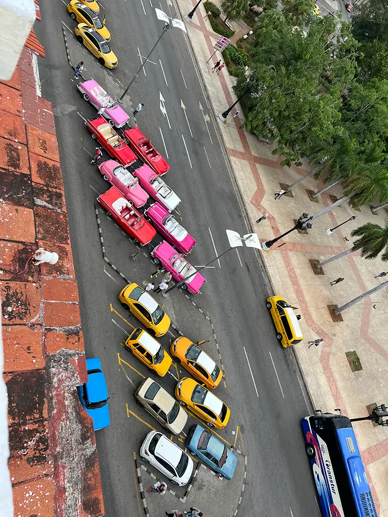 Blick von oben auf bunte Oldtimer und gelbe Taxis in Havanna auf Kuba