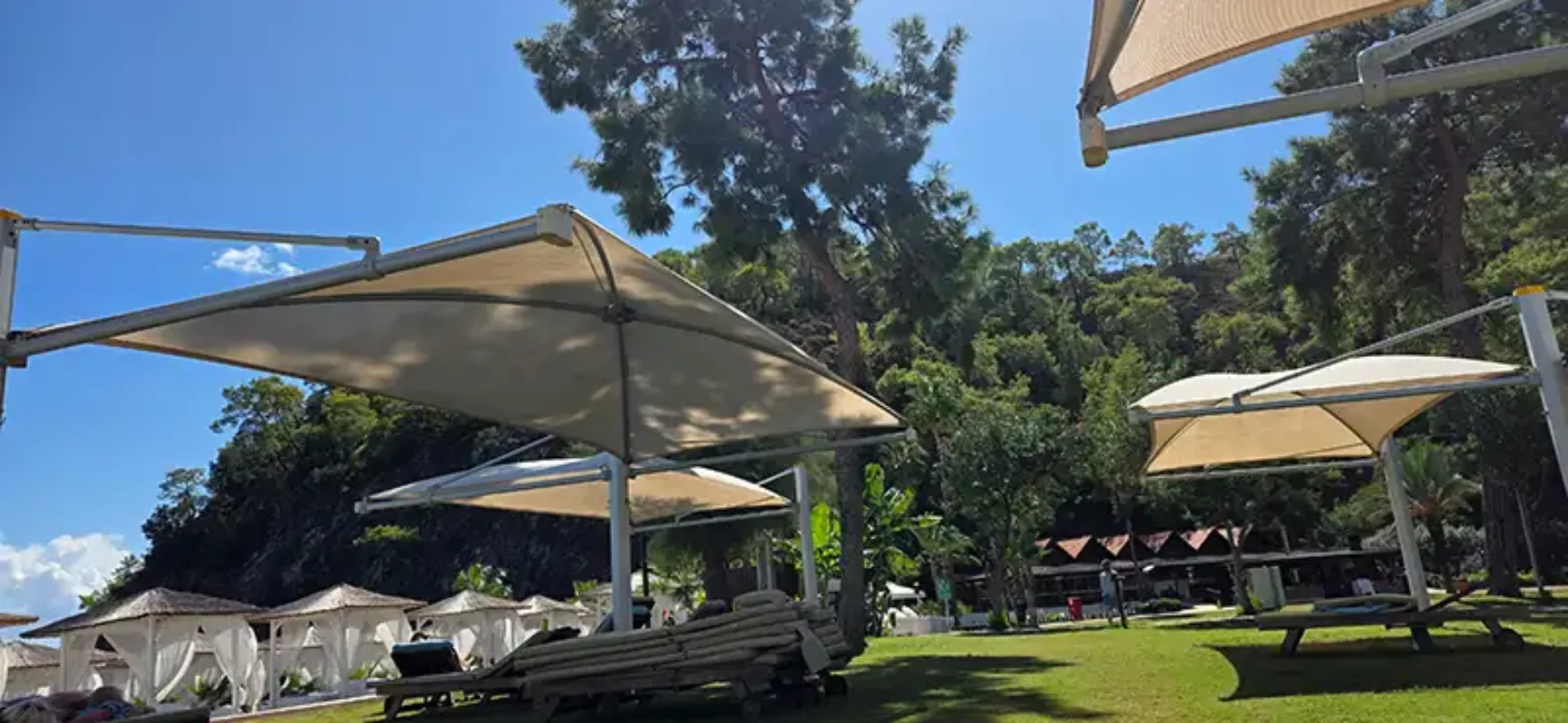 Sonnige Liegewiese im Robinson Camyuva in Kemer mit Sonnensegeln, Pinien und entspannter Clubatmosphäre