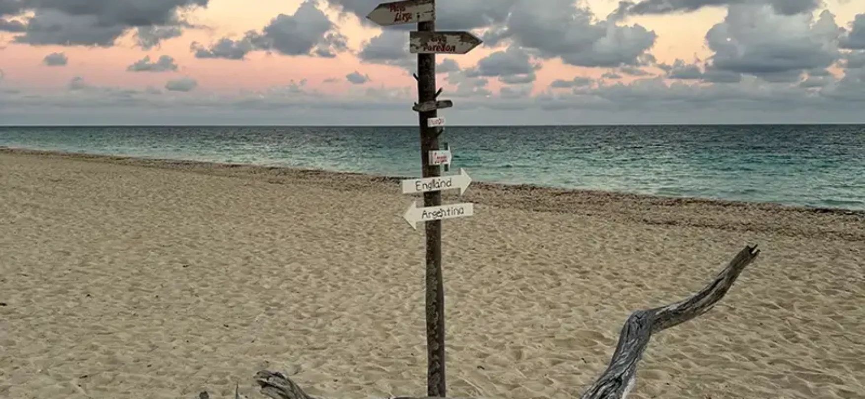 Strand auf Kuba mit Wegweiser, Treibholz und Abendstimmung am Meer